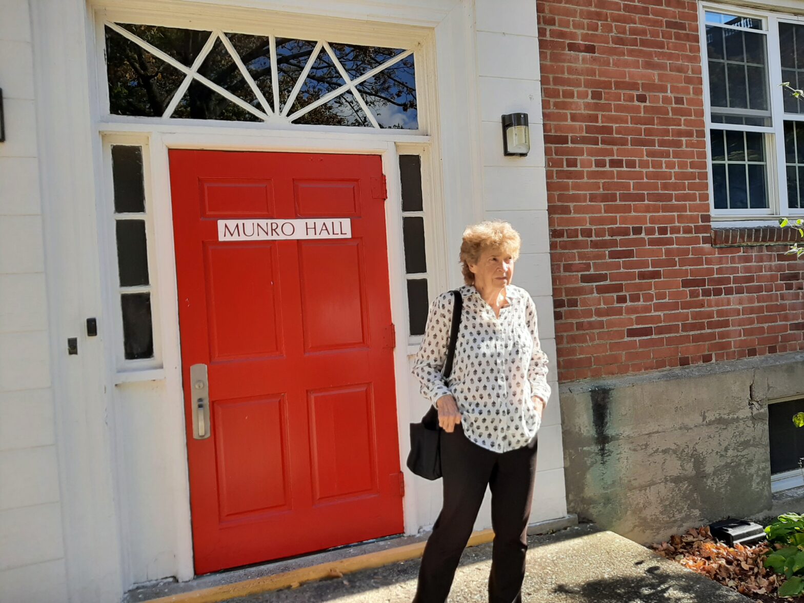 Woman standing outside a red door labeled 'Employee Entrance'.