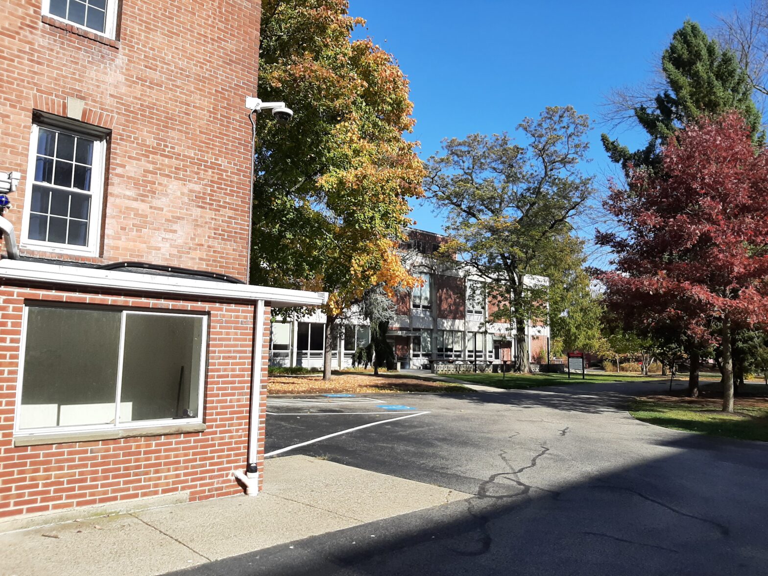 A sunny autumn day on a quiet street with colorful trees and brick buildings.